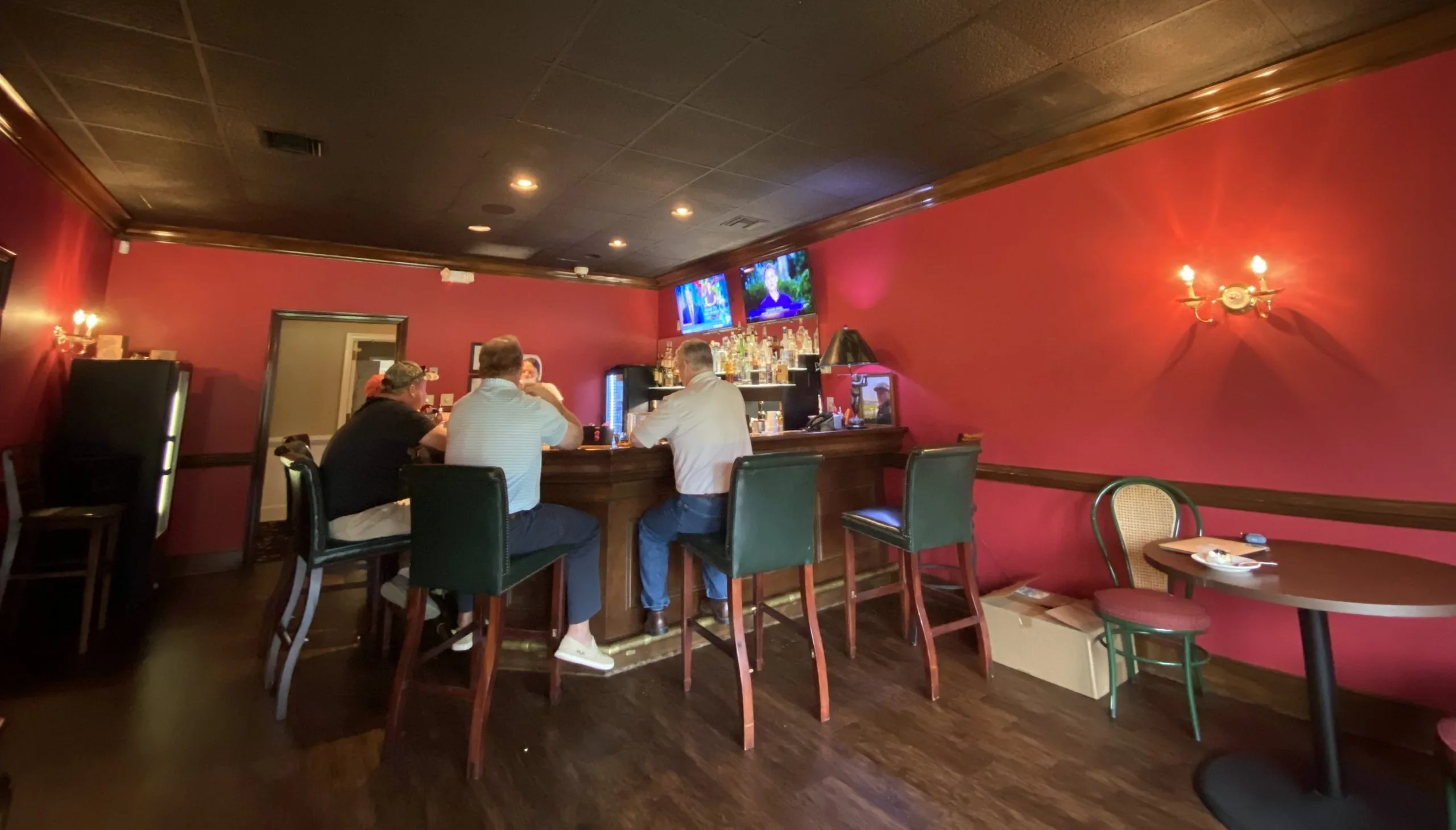 The Red Bar, a cozy corner bar at Darlington Country Club where three men watch the news on television